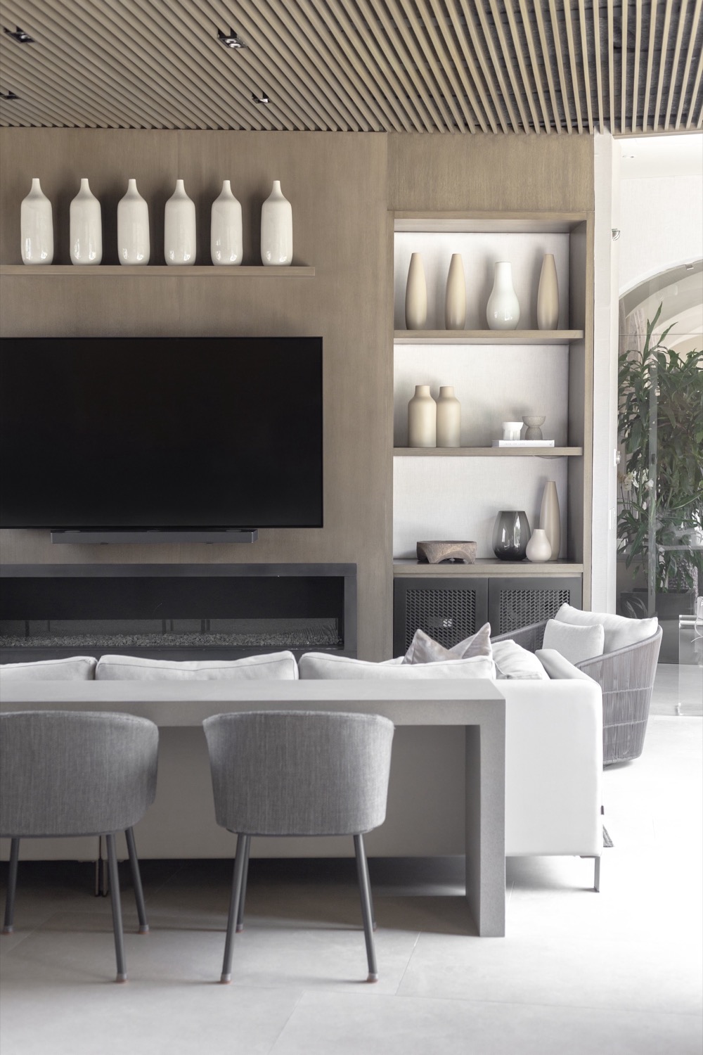 Zaga — media wall with fireplace, timber slat ceiling and ceramic vessels